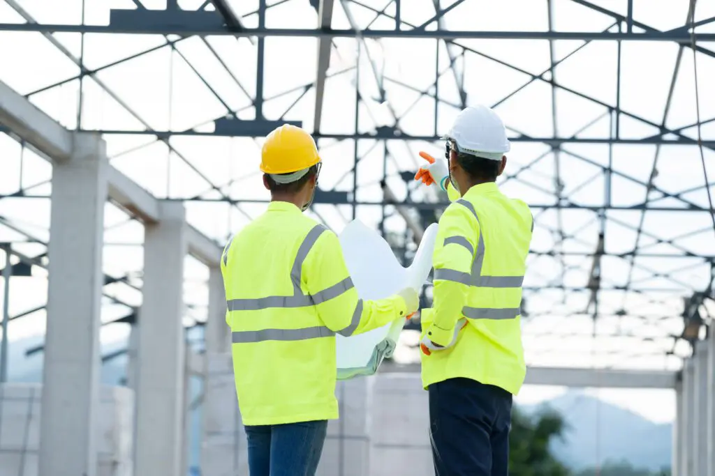 Two construction workers reviewing blueprints on site