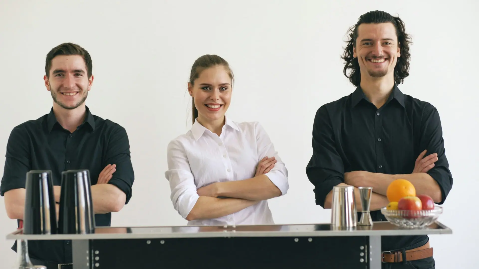 Three smiling people behind a bar counter
